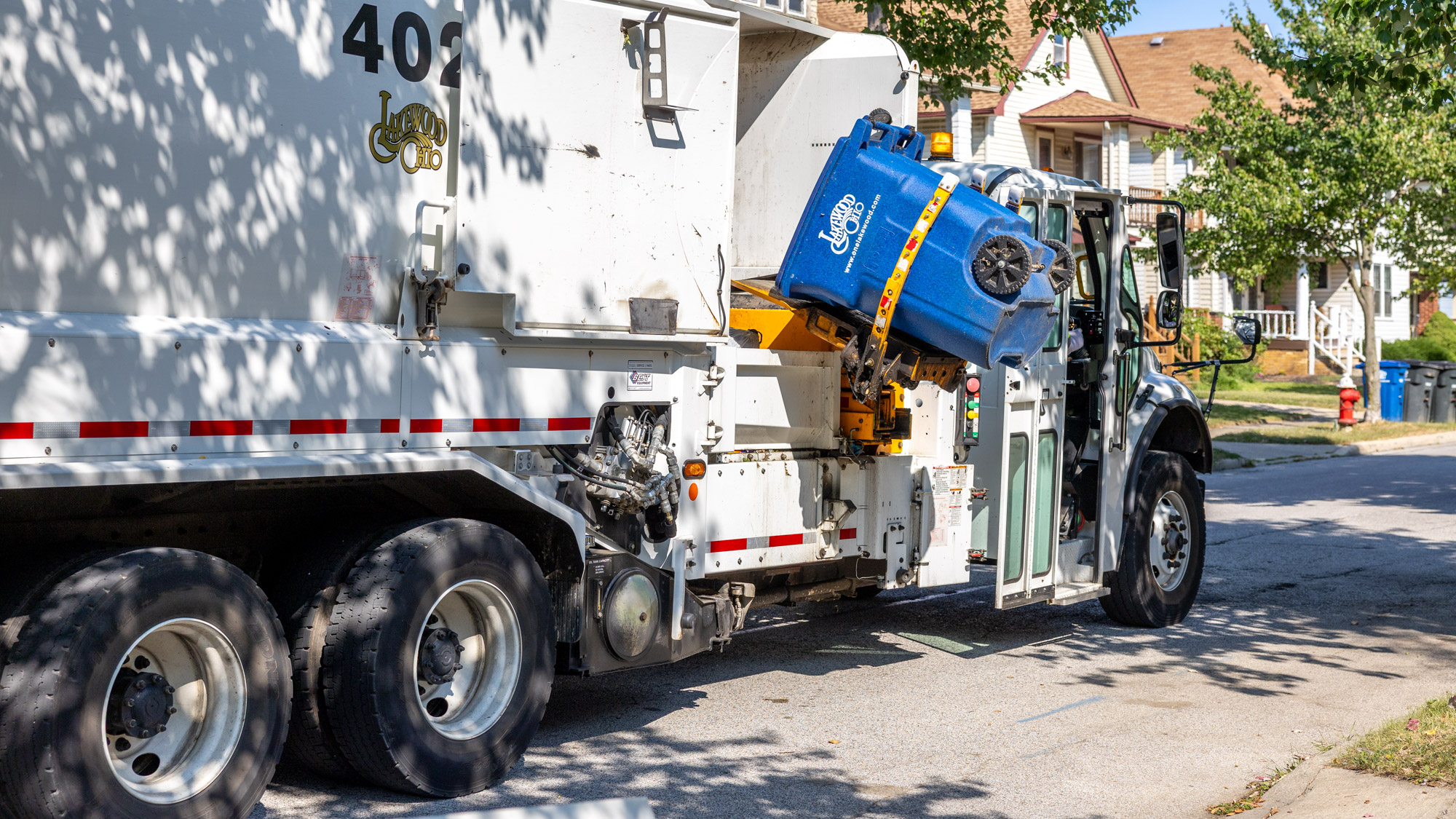 An automated Lakewood recycling truck dumping recycling materials from a blue bin into the truck.