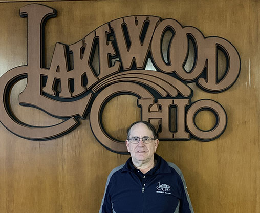 Bruce Hare in front of a wood Lakewood Ohio logo.