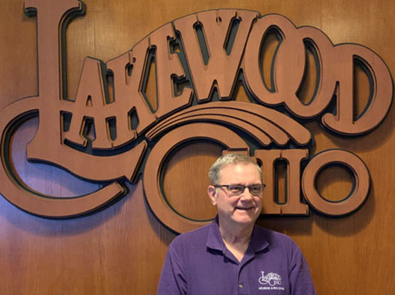 Charles Huber in front of a wood Lakewood Ohio logo.