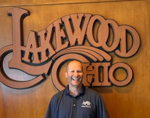 David Lawrence in front of a wood Lakewood Ohio logo.