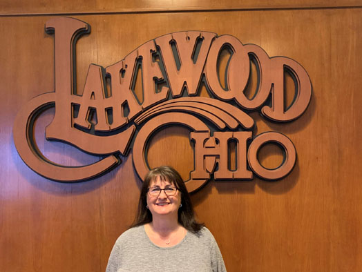 Diana Graff in front of a wood Lakewood Ohio logo.