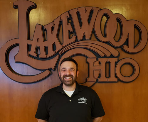 Goran Najdenovski in front of a wood Lakewood Ohio logo.