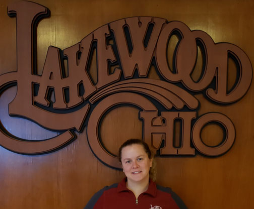Jessica Braun in front of a wood Lakewood Ohio logo.