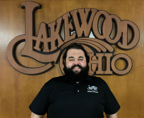 Justin Maskaluk in front of a wood Lakewood Ohio logo.