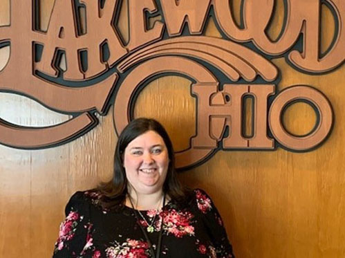 Kelly McCafferty in front of a wood Lakewood Ohio logo.