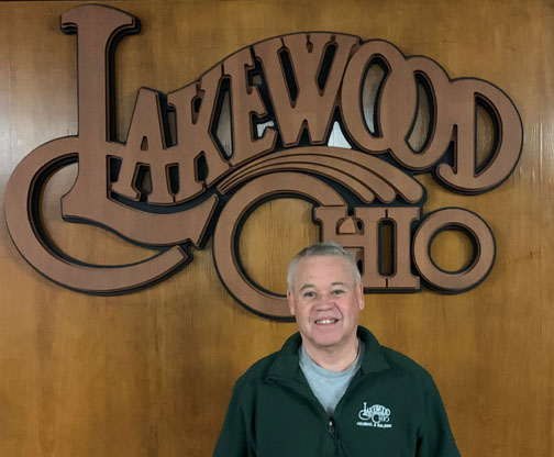 Kevin Kelley in front of a wood Lakewood Ohio logo.