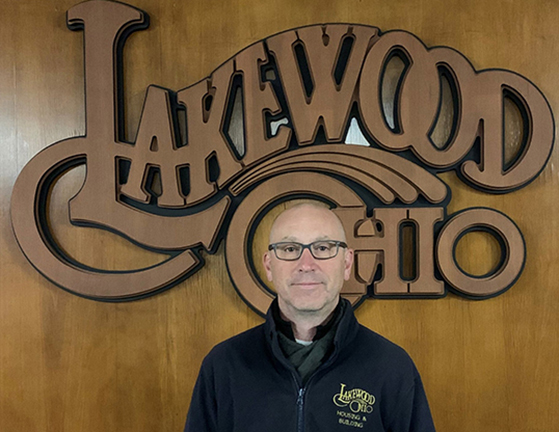 Mark Jewitt in front of a wood Lakewood Ohio logo.