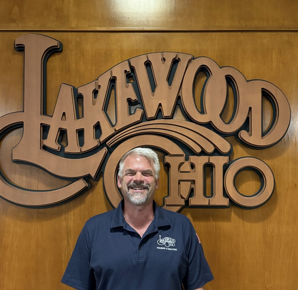 Michael Doup in front of a wood Lakewood Ohio logo.