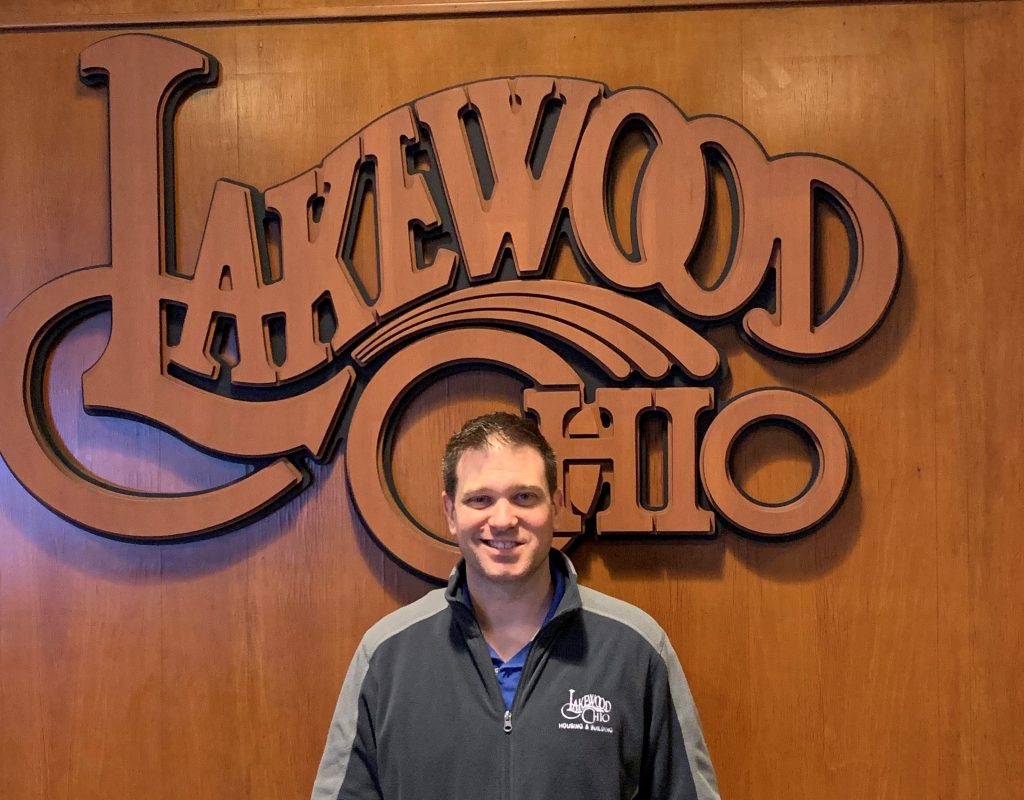 Mike Reilley in front of a wood Lakewood Ohio logo.
