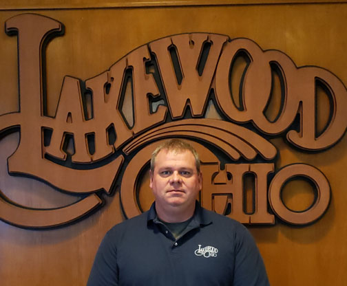 Ron Schwaben in front of a wood Lakewood Ohio logo.